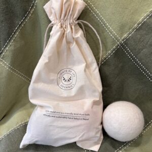 Cotton satchel holds two dryer balls next to a third dryer ball.